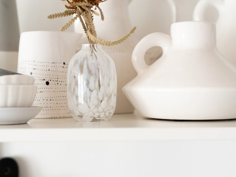 a white shelf topped with lots of white vases
