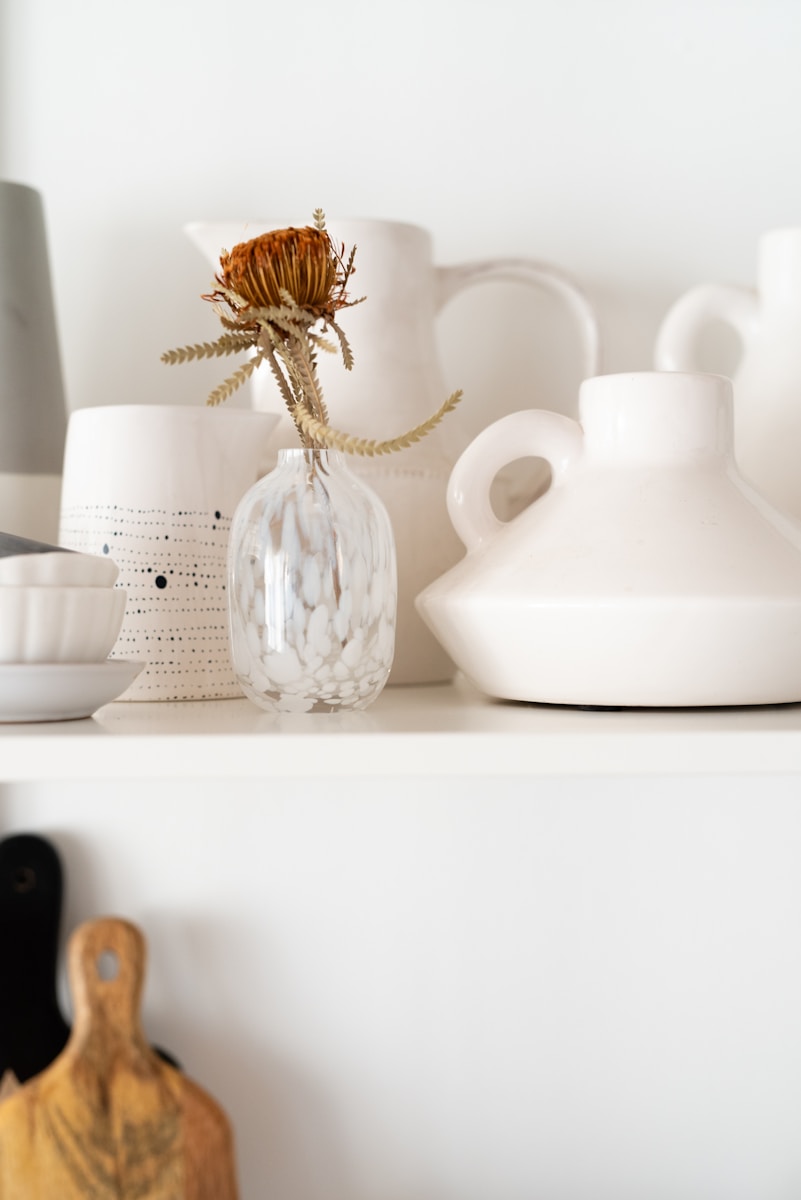 a white shelf topped with lots of white vases